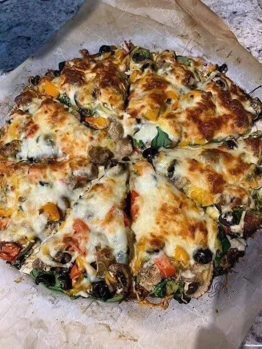 Delicious Fathead pizza slice topped with white sauce, chicken, mushrooms, and spinach