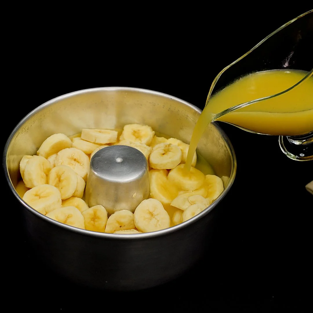 Un'immagine di banane e arance fresche su un tavolo di legno.