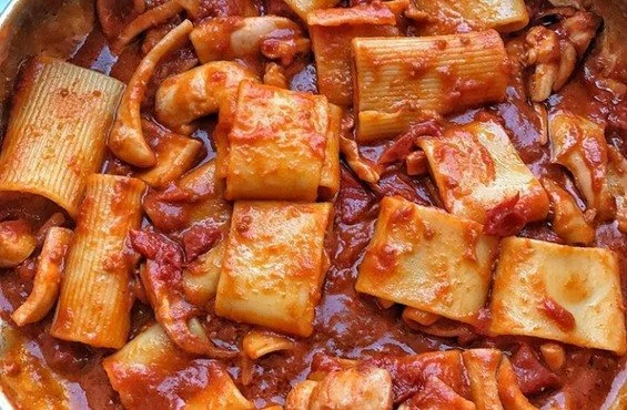 Piatto di calamarata con calamari fresco e aromi mediterranei