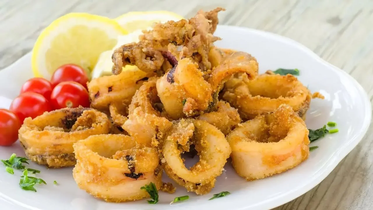 Calamars frits croccanti serviti con salsa di accompagnamento.