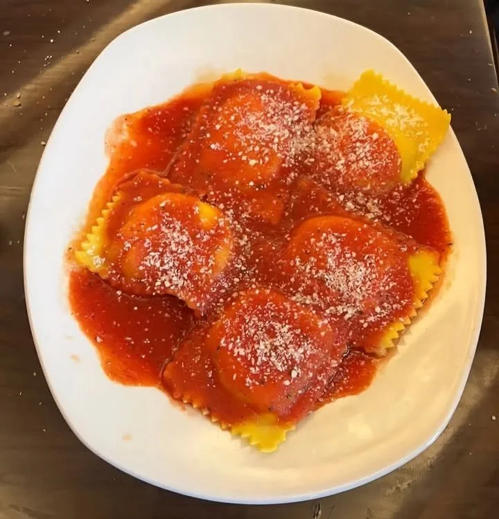 Ravioli al formaggio serviti con salsa e decorazioni fresche