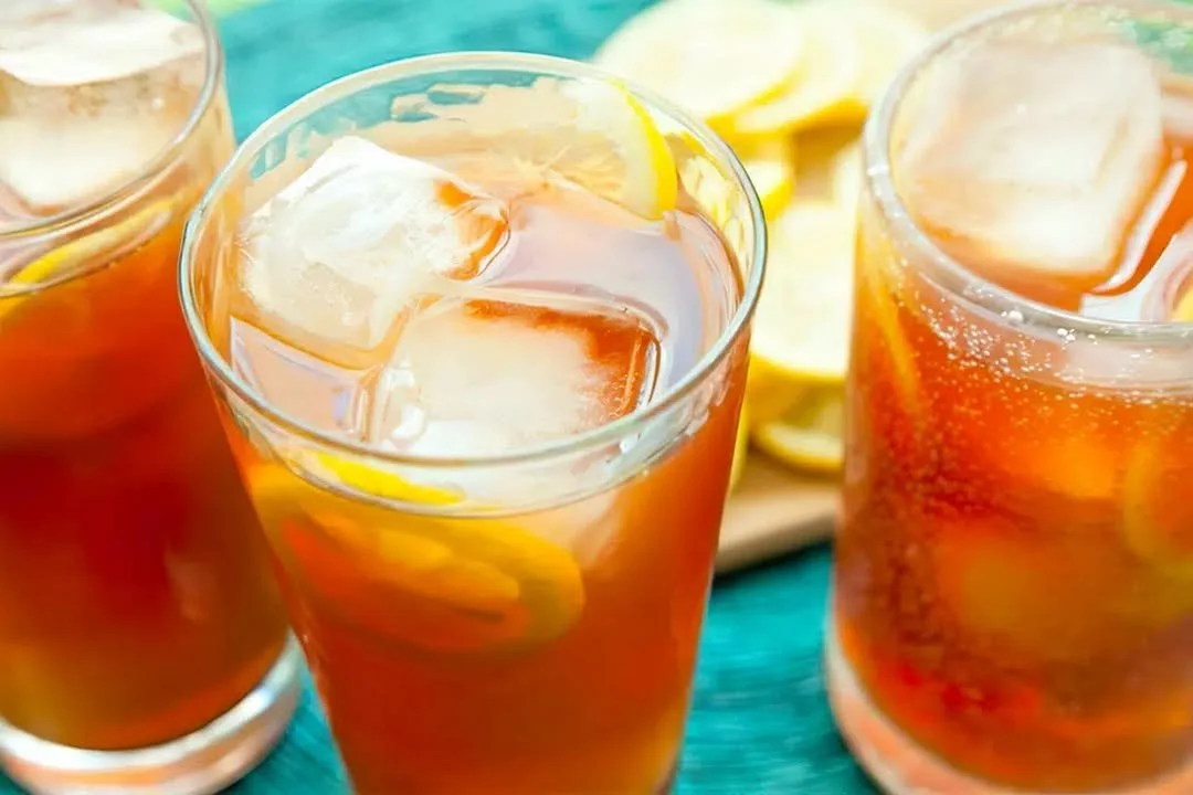 Una fresca tazza di Tè Glacé con ghiaccio e fette di limone.