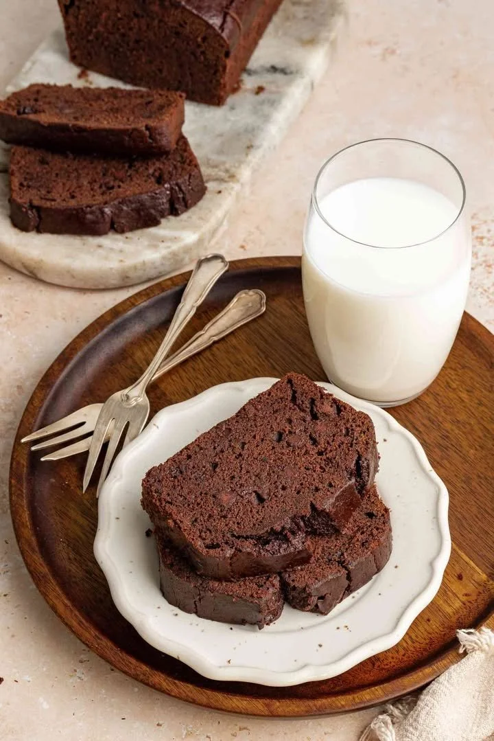 Sliced chocolate banana bread on a wooden cutting board with chocolate chips