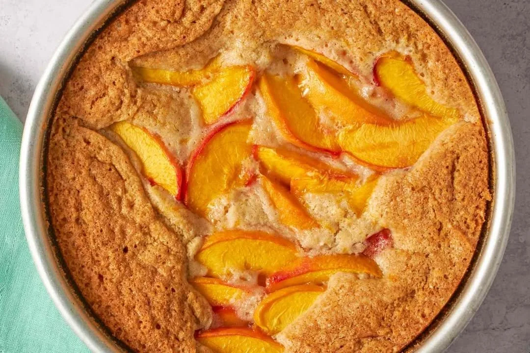 Delicious rustic peach spoon cake served in a bowl with fresh peaches